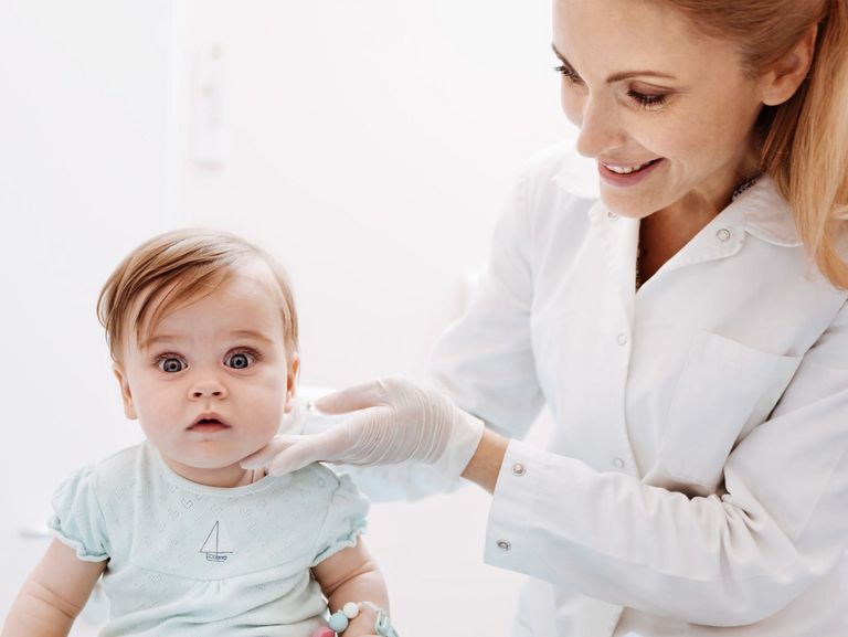 Ärztin untersucht ein Kleinkind mit dicker Backe