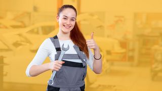 Junge Frau in Werkstatt-Arbeitskleidung mit Schraubenschlüssel