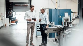 Arbeitgeber im Handwerk Geschäftsleute unterhalten sich in einer Produktionshalle