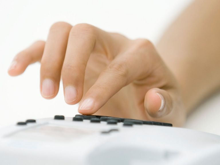 Frauenhand beim Wählen einer Telefonnummer