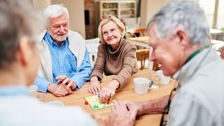 Wohngruppenzuschuss Wohngruppe mit Rentnerin beim gemeinsamen Spielen