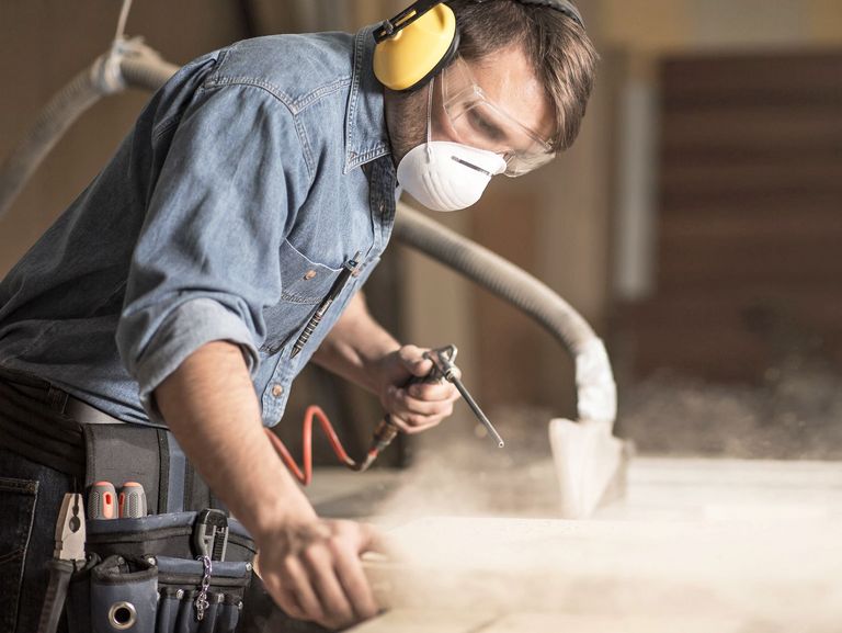 Schreiner mit Hör- und Mundschutz bei der Arbeit