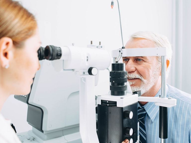Augenärztin untersucht mit einem Spezialgerät die Augen eines älteren Mannes