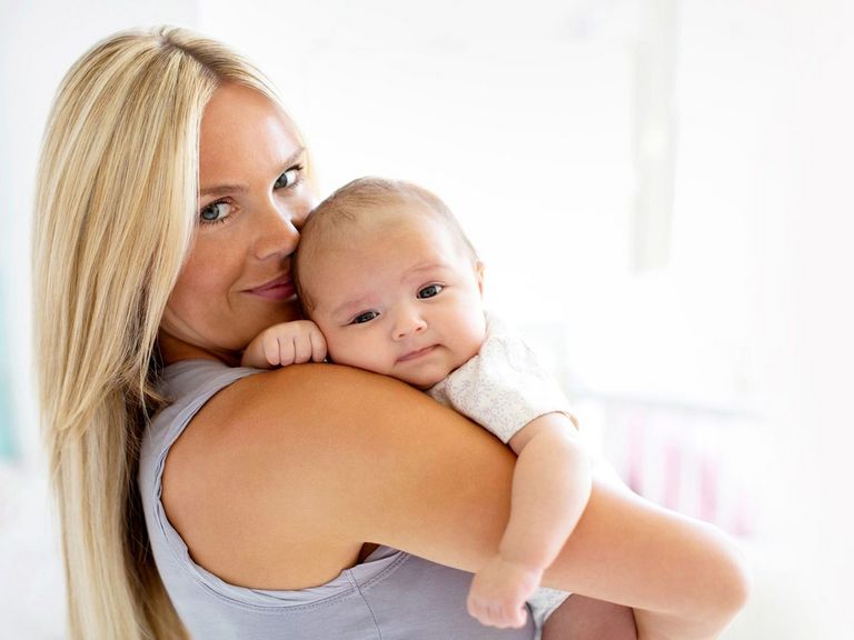 Mutter hält ihr Baby auf dem Arm und lächelt