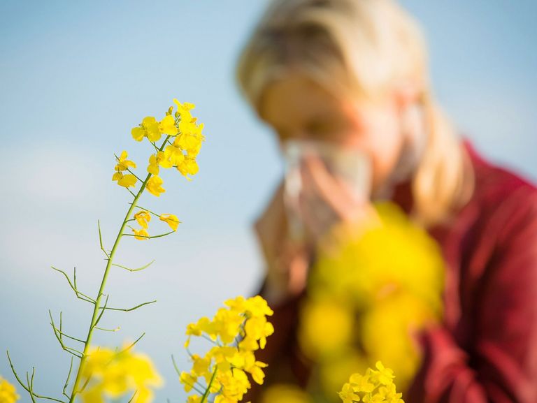 Frau hat Heuschnupfen auf einer blühenden Wiese