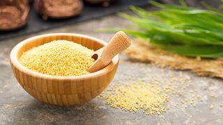 Bulgur, Couscous & Co. Bambusschale mit trockenem Bulgur und einem kleinen Holzschäufelchen