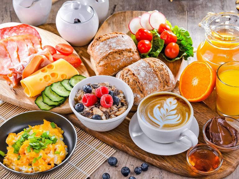 Rustikaler Holztisch gedeckt mit einem reichhaltigem und abwechslungsreichen Frühstück