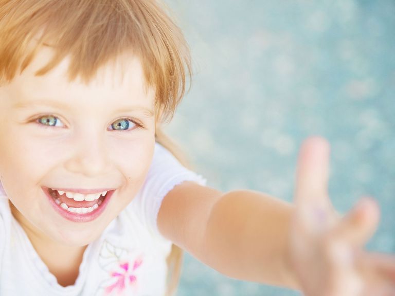 Kleinkind schaut lachend nach oben in die Kamera