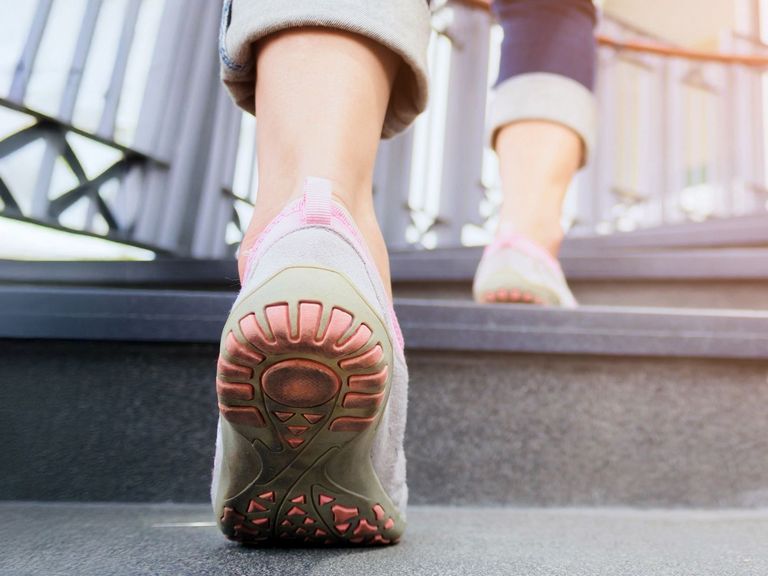 Detailaufnahme von Frauenfüßen in Schuhen, die eine Treppe hoch laufen