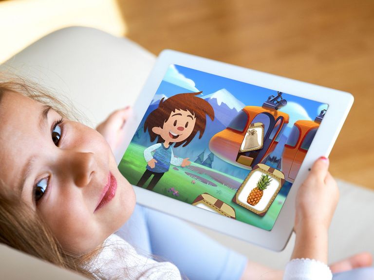 Mädchen sitzt auf der Couch mit einem Tablet in der Hand