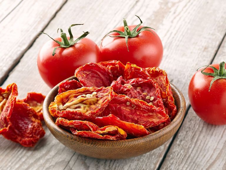 frische und getrocknete Tomaten stehen auf einem Holztisch