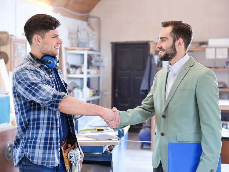 Handschlag vom Arbeitgeber mit seinem Azubi in einer Werkstatt