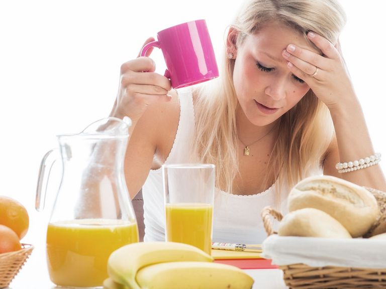 Junge Frau am Frühstückstisch fühlt sich nicht gut