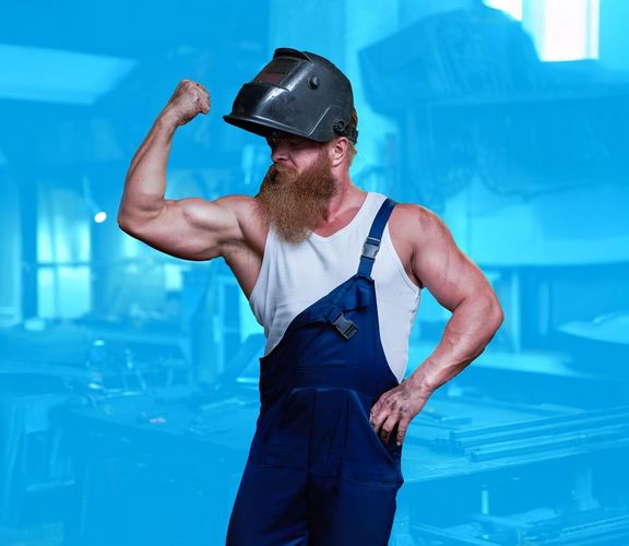 Muskelprotz in Handwerkerkleidung zeigt mit einem Arm seine Muskeln