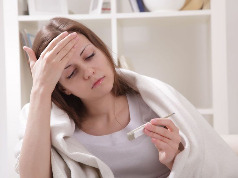 Frau mit Erkältung misst Körpertemperatur