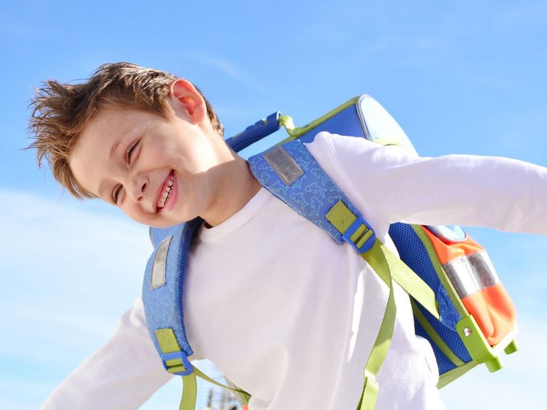 Glücklicher Junge trägt Schulranzen im Freien