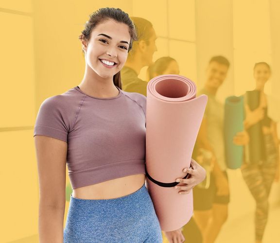 Junge Frau im Sportraum mit einer Yoga-Matte in der Hand