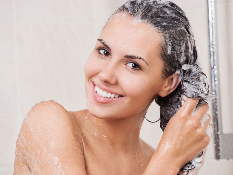 Frau wäscht sich unter der Dusche die Haare