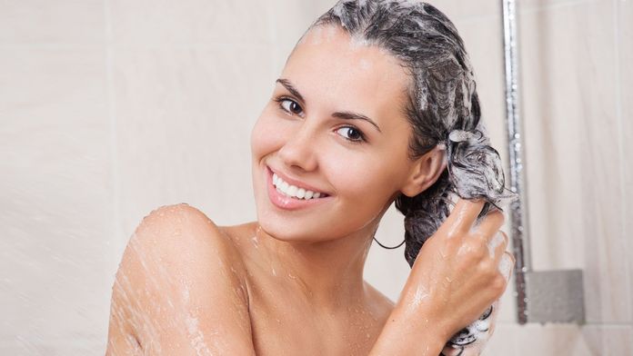 Frau wäscht sich unter der Dusche die Haare
