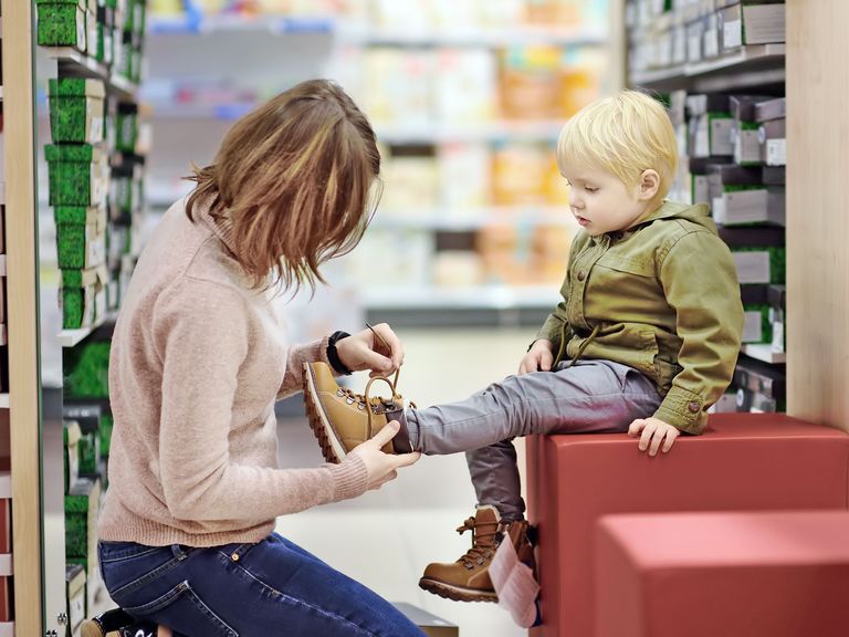 Mutter und ihr kleiner Sohn beim Winterschuhkauf in einem Geschäft