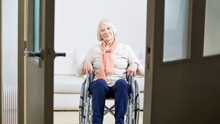 Wohnumfeldverbesserung Rentnerin im Rollstuhl vor einer Tür in ihrer Wohnung