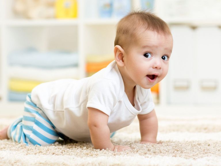 Baby krabbelt auf einem weichen Teppich