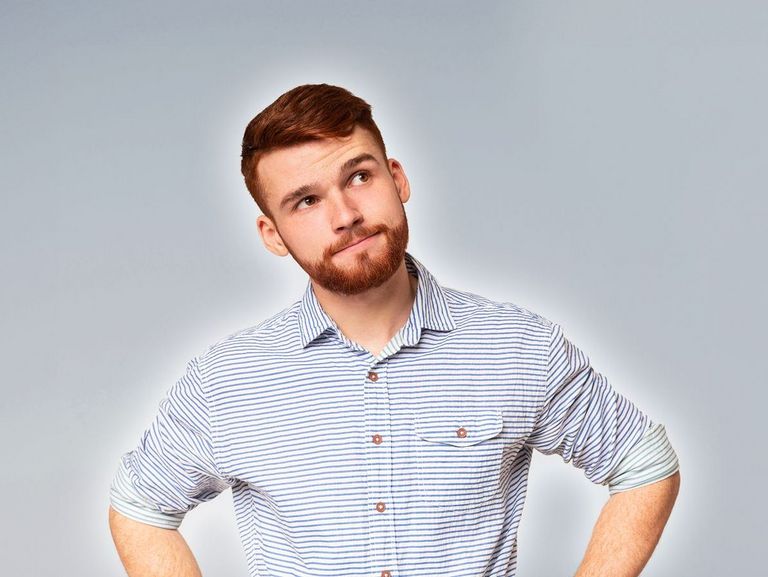 Junger Mann mit Bart schaut fragend und überlegend nach oben rechts