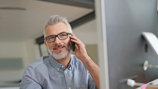 Mann sitzt vor einem PC-Bildschirm und berät einen Anrufer am Telefon