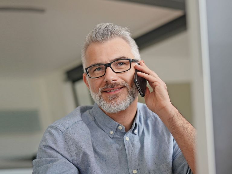 Mann sitzt vor einem PC-Bildschirm und berät einen Anrufer am Telefon