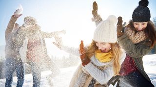 Mehrere Freunde lachen bei einer lustigen Schneeballschlacht