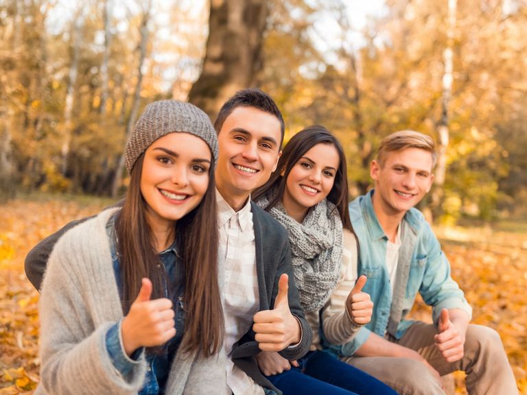 Jugendliche in herbstlicher Kleidung mit Daumen hoch