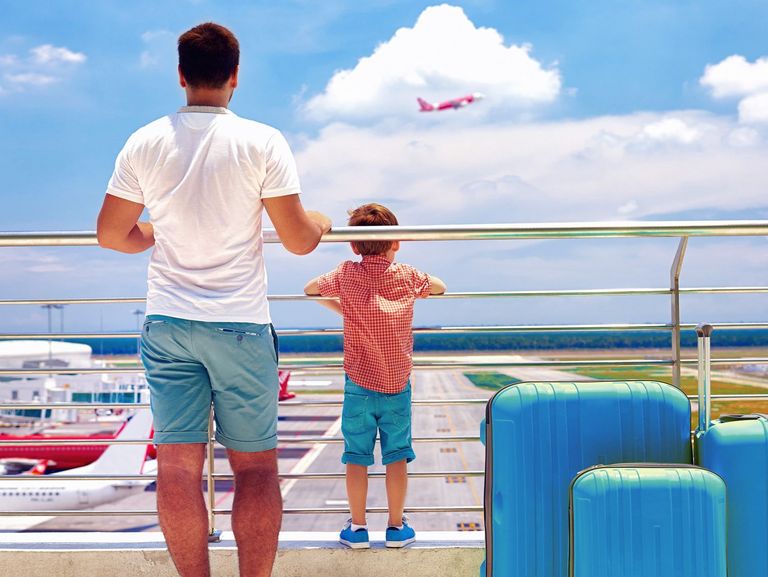 Vater und Sohn stehen mit ihren Koffern an einem Aussichtpunkt am Flughafen