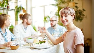 Trinken bei Mahlzeiten Freunde sitzen zum gemeinsamen Essen an einem Tisch