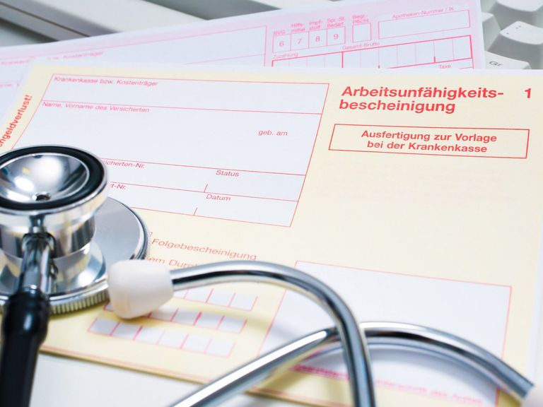 Krankenschein auf einem Arzt-Schreibtisch