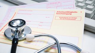 Krankenschein auf einem Arzt-Schreibtisch