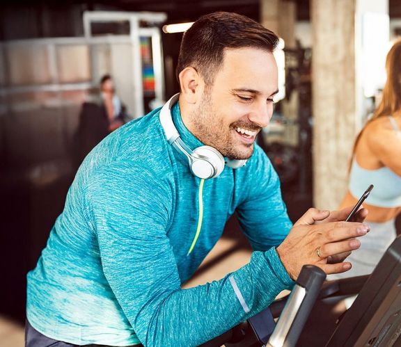 Musik im Training Mann im Sportdress sucht sich für sein Training die richtige Musik auf seinem Smartphone aus