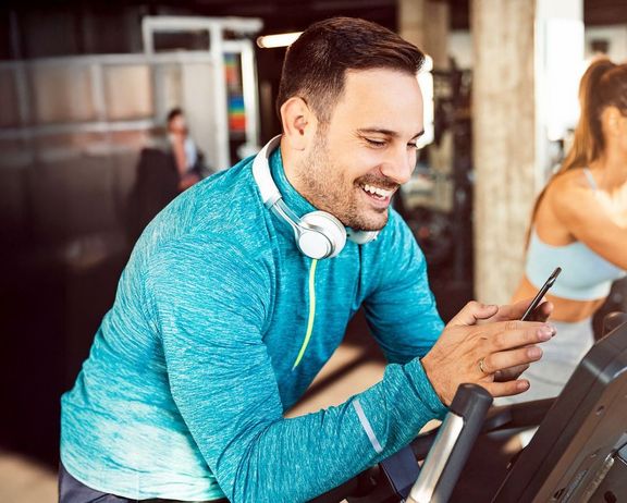 Musik im Training Mann im Sportdress sucht sich für sein Training die richtige Musik auf seinem Smartphone aus