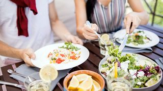 Mann und Frau sitzen an einem gedeckten Tisch mit Speisen der Mediterranen Küche