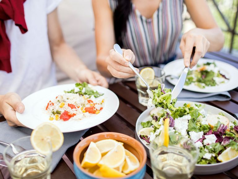 Mann und Frau sitzen an einem gedeckten Tisch mit Speisen der Mediterranen Küche