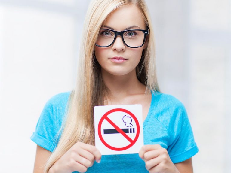 Frau hält ein Rauchverbotsschild