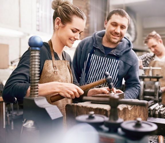 Macher im Handwerk kleines Team an Mitarbeitern arbeitet mit Freude in einer Werkstatt