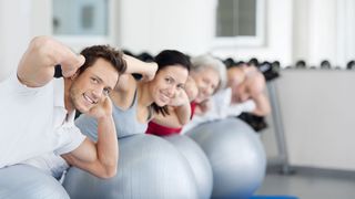 Rückengesundheit Gruppe Sporttreibender macht eine Übung auf silberfarbenen Gymnastikbällen