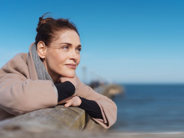 Frau im Portrait auf einer Seebrücke an einem Strand bei Sonnenschein