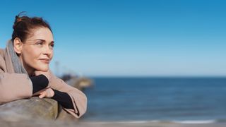 Frau im Portrait auf einer Seebrücke an einem Strand bei Sonnenschein