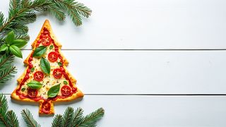 Adventszeit genießen Pizza mit Tomaten und Basilikum in Form eines Tannenbaums auf einem grauen Holztisch