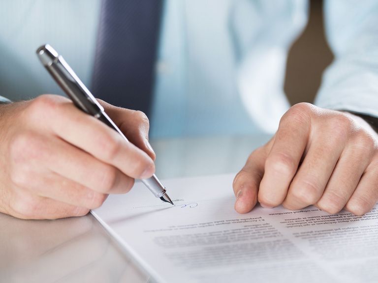 Mann unterschreibt ein Schriftstück