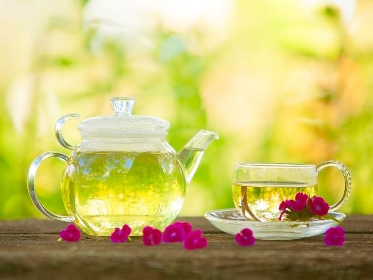 Glaskanne mit selbstgemachtem Tee auf einem Holztisch