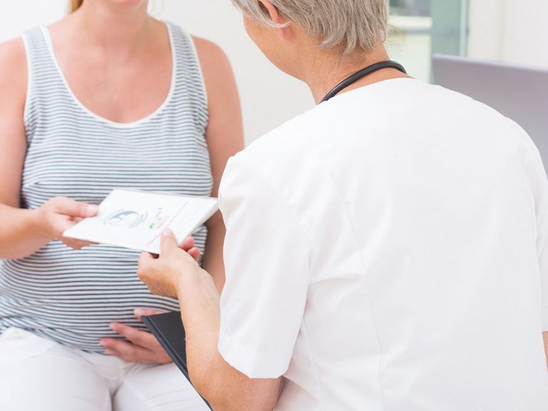 Frauenärztin überreicht einer Schwangeren einen Mutterpass