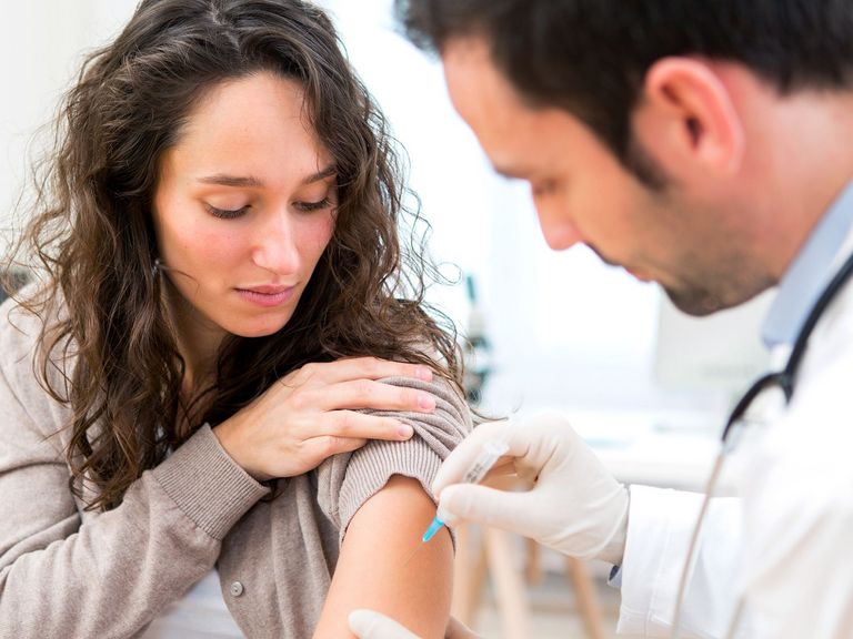 Arzt impft eine Frau im Oberarm