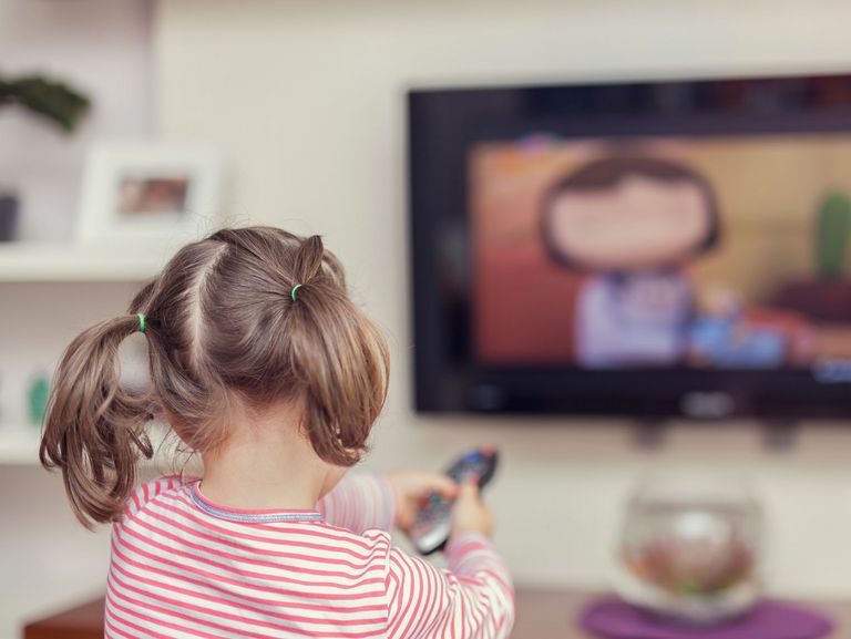 Kleines Mädchen sitzt allein vor einem Fernseher